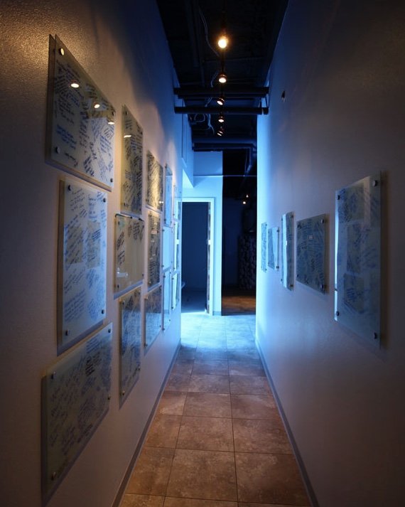 Glass panels of handwritten guest experiences lining The Float Spot studio hallway